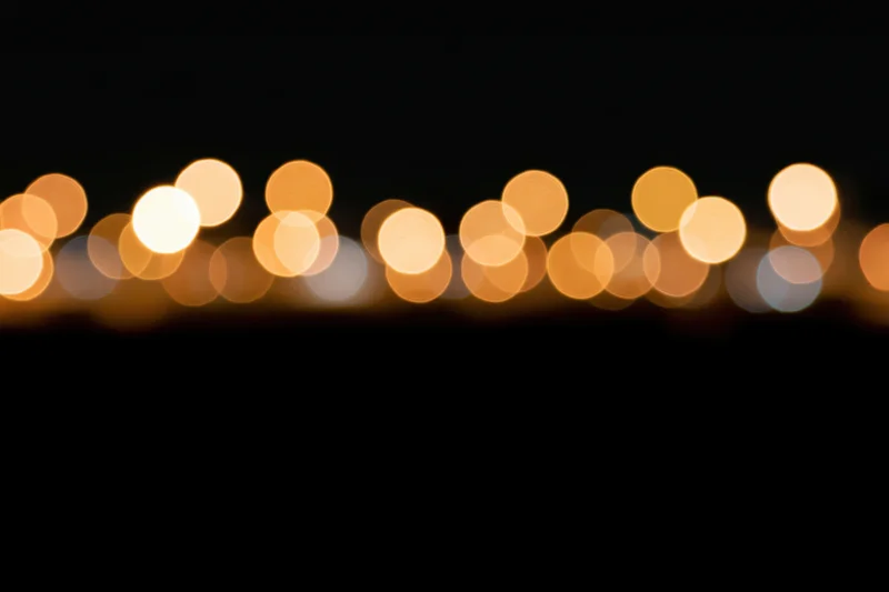 Golden bokeh circles scattered across the upper portion of a dark frame, creating a soft glowing background with copyspace below