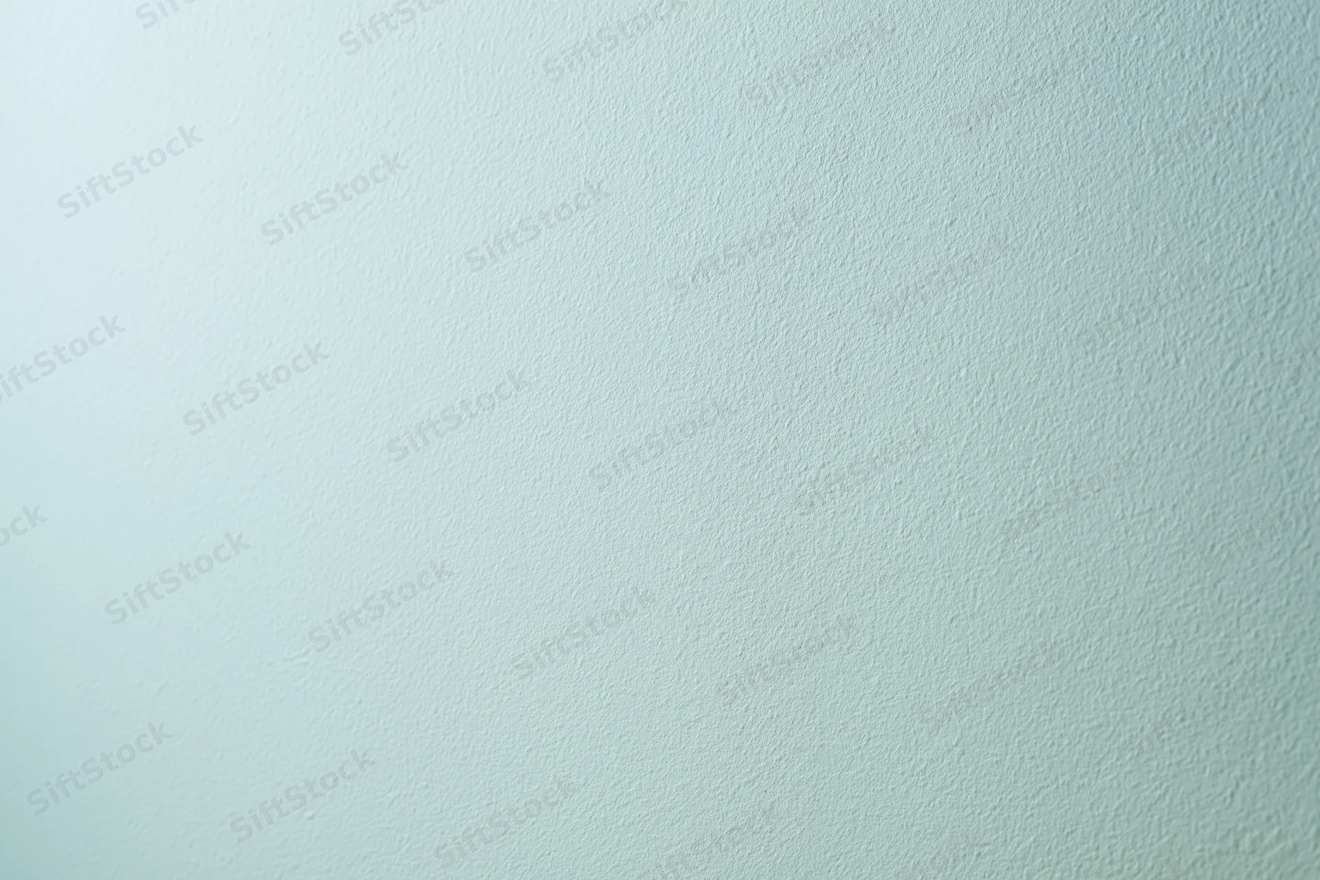 Plain painted wall surface filling the frame with smooth texture and light mint green color gradient