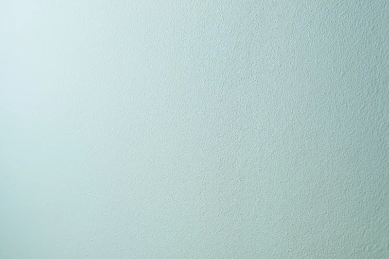 Plain painted wall surface filling the frame with smooth texture and light mint green color gradient