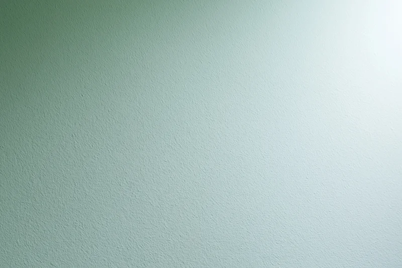 Smooth painted wall surface filling the frame with light green to white gradient and subtle texture