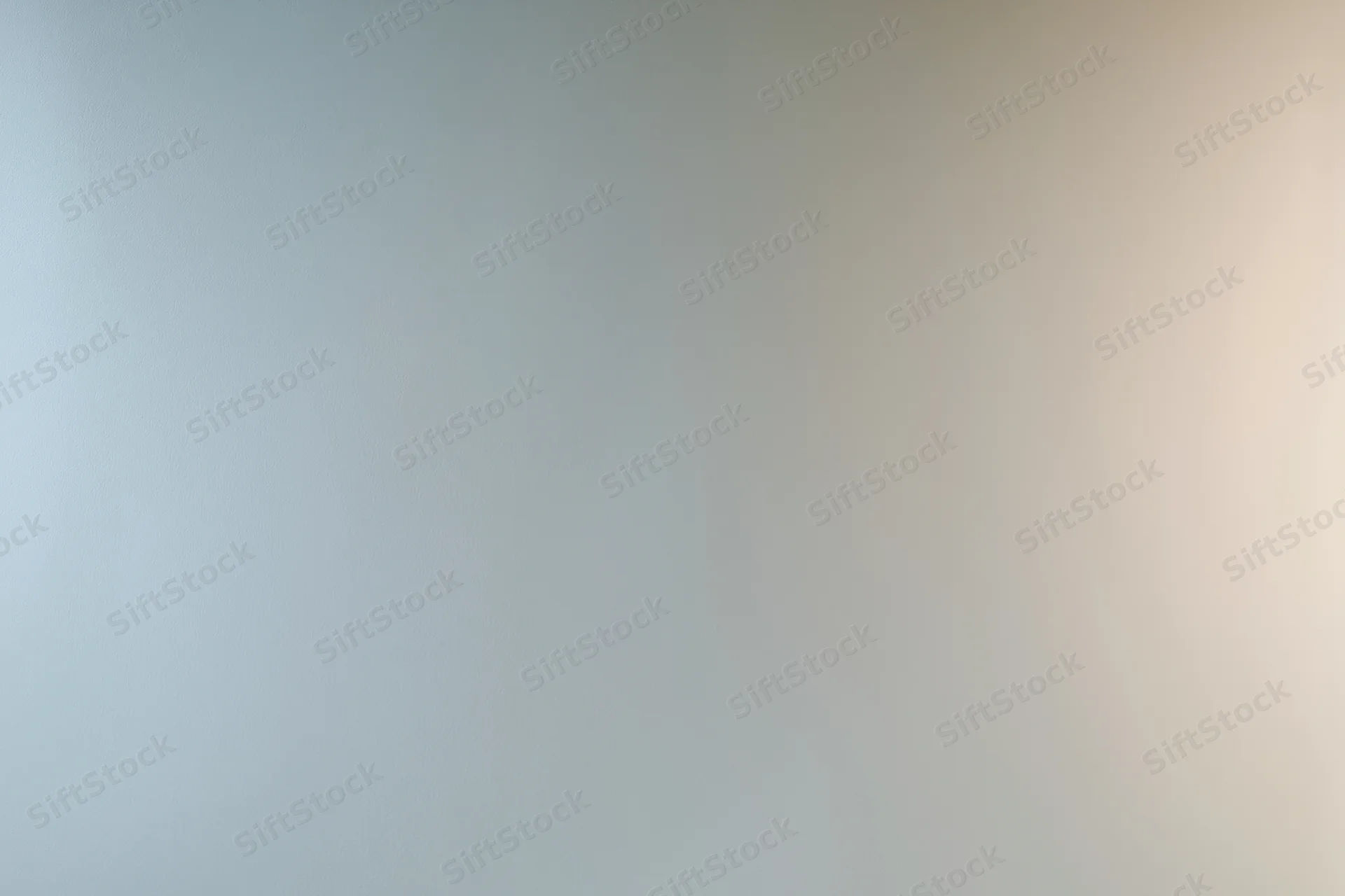 Smooth gradient surface transitioning from light gray to beige in a studio backdrop