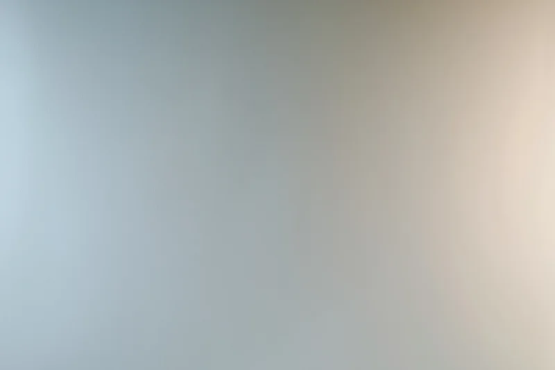 Smooth gradient surface transitioning from light gray to beige in a studio backdrop
