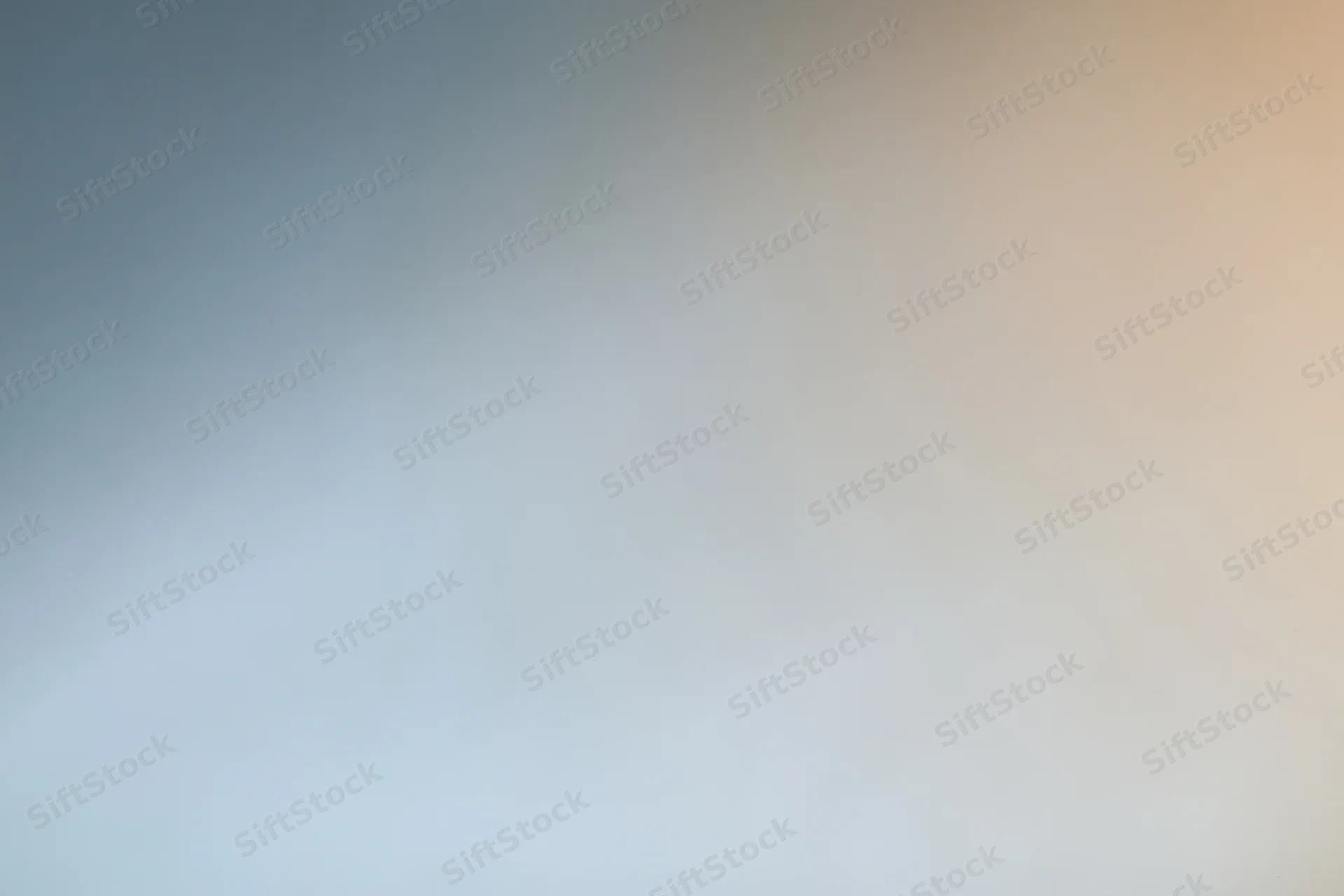 Smooth color gradient transitioning from blue to beige across a plain studio backdrop