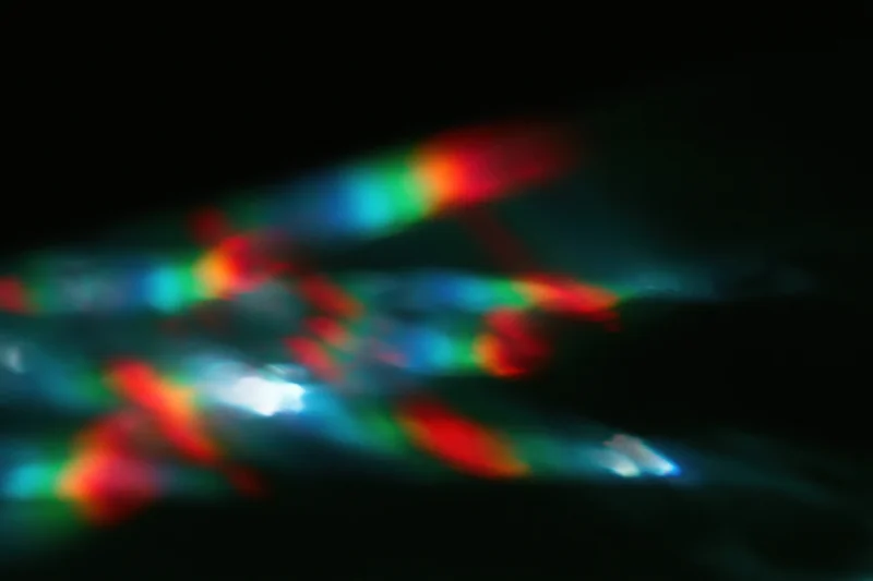 Prismatic light leaks scattered across a pure black background
