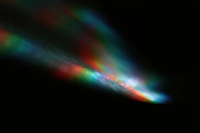 Prismatic light leaks scattered across a pure black background