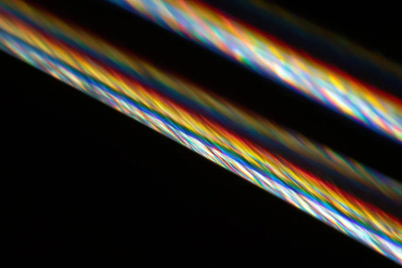 Prismatic light streaks diagonally scattered across dark background