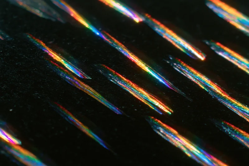 Prismatic light streaks arranged diagonally across a dark surface