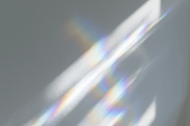 Rainbow light refraction rays scattered across a white wall surface