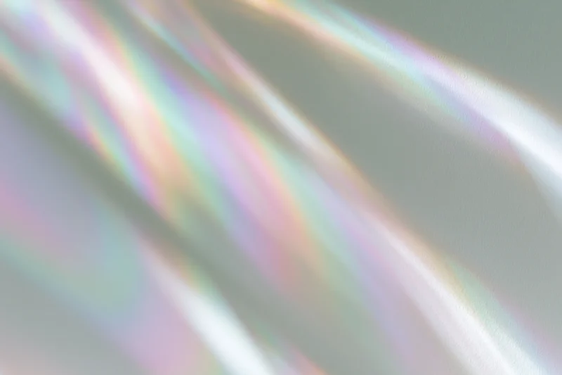 Rainbow light refraction streaks falling across a pale white surface