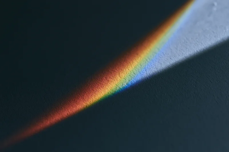 Rainbow spectrum light projection cast diagonally across a dark textured surface