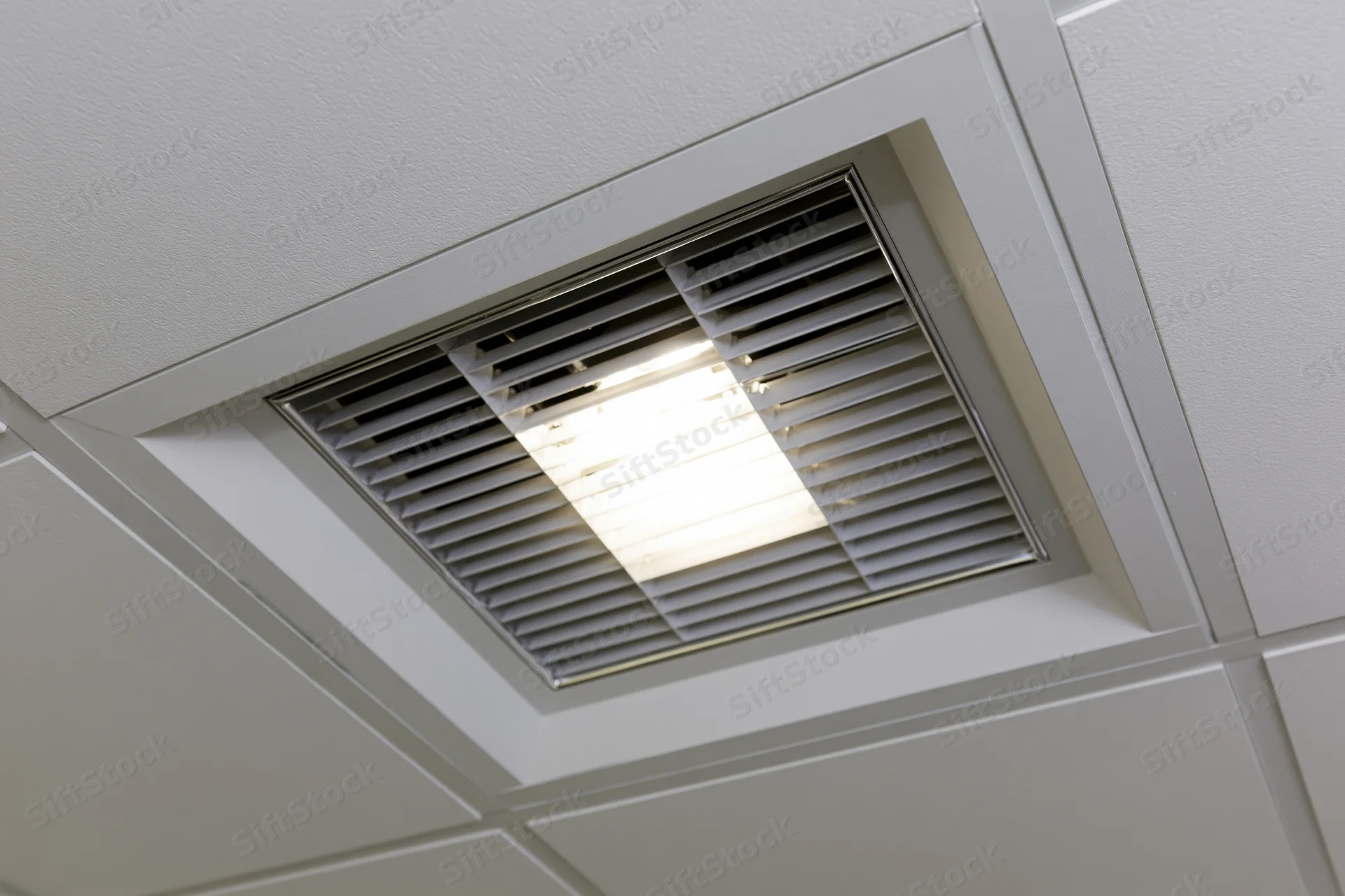 Recessed fluorescent light fixture mounted in a dropped ceiling grid