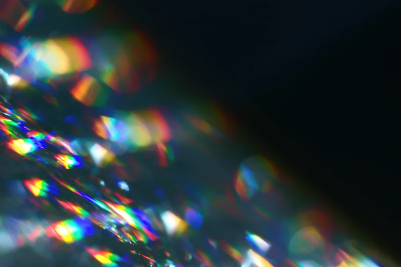 Scattered prism light reflections on a dark surface with soft defocus
