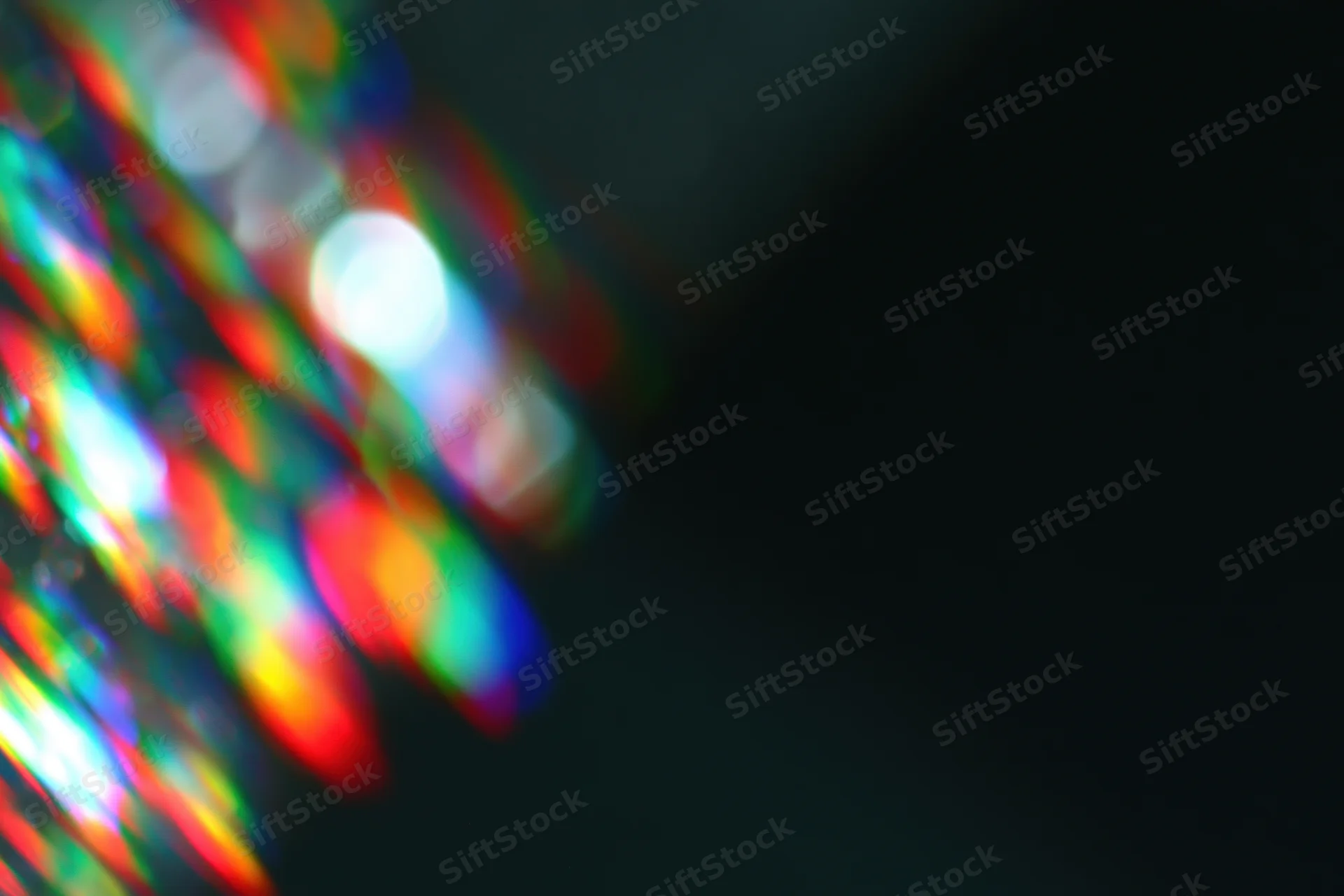 Scattered prism light reflections on a dark surface with soft blur and bokeh effect