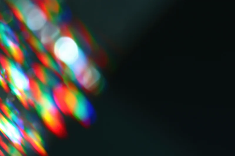 Scattered prism light reflections on a dark surface with soft blur and bokeh effect