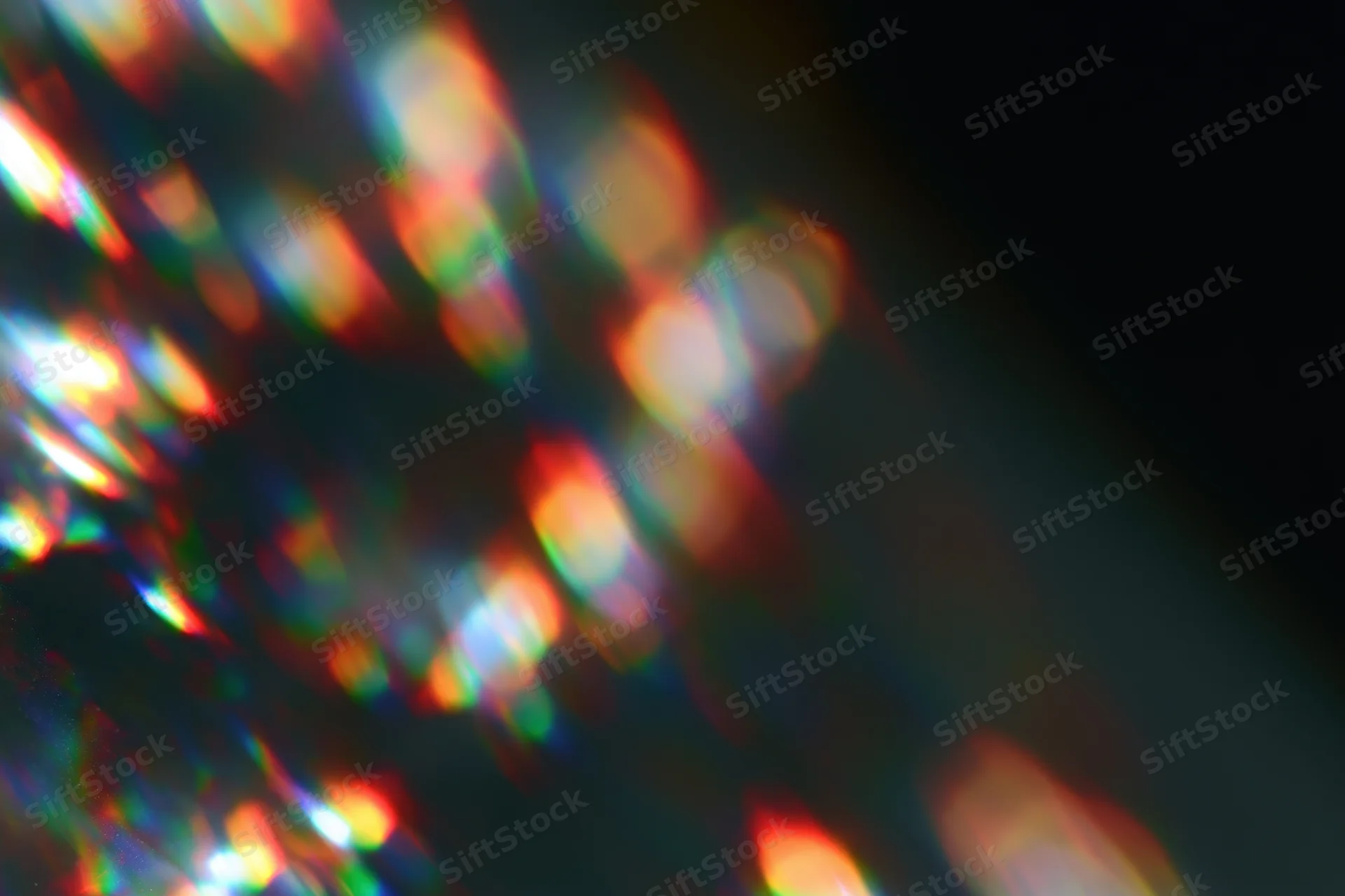 Scattered prism light reflections on a dark surface with soft defocus