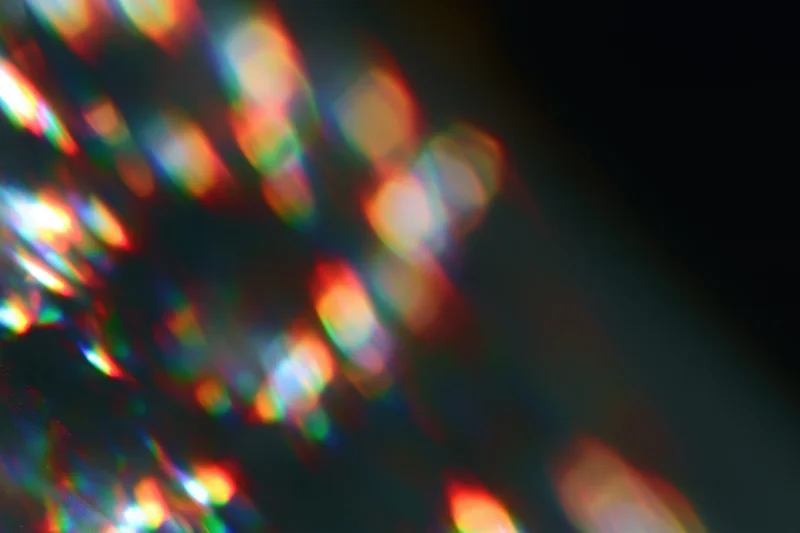Scattered prism light reflections on a dark surface with soft defocus