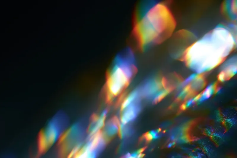 Scattered prism light reflections on a dark surface with soft defocus