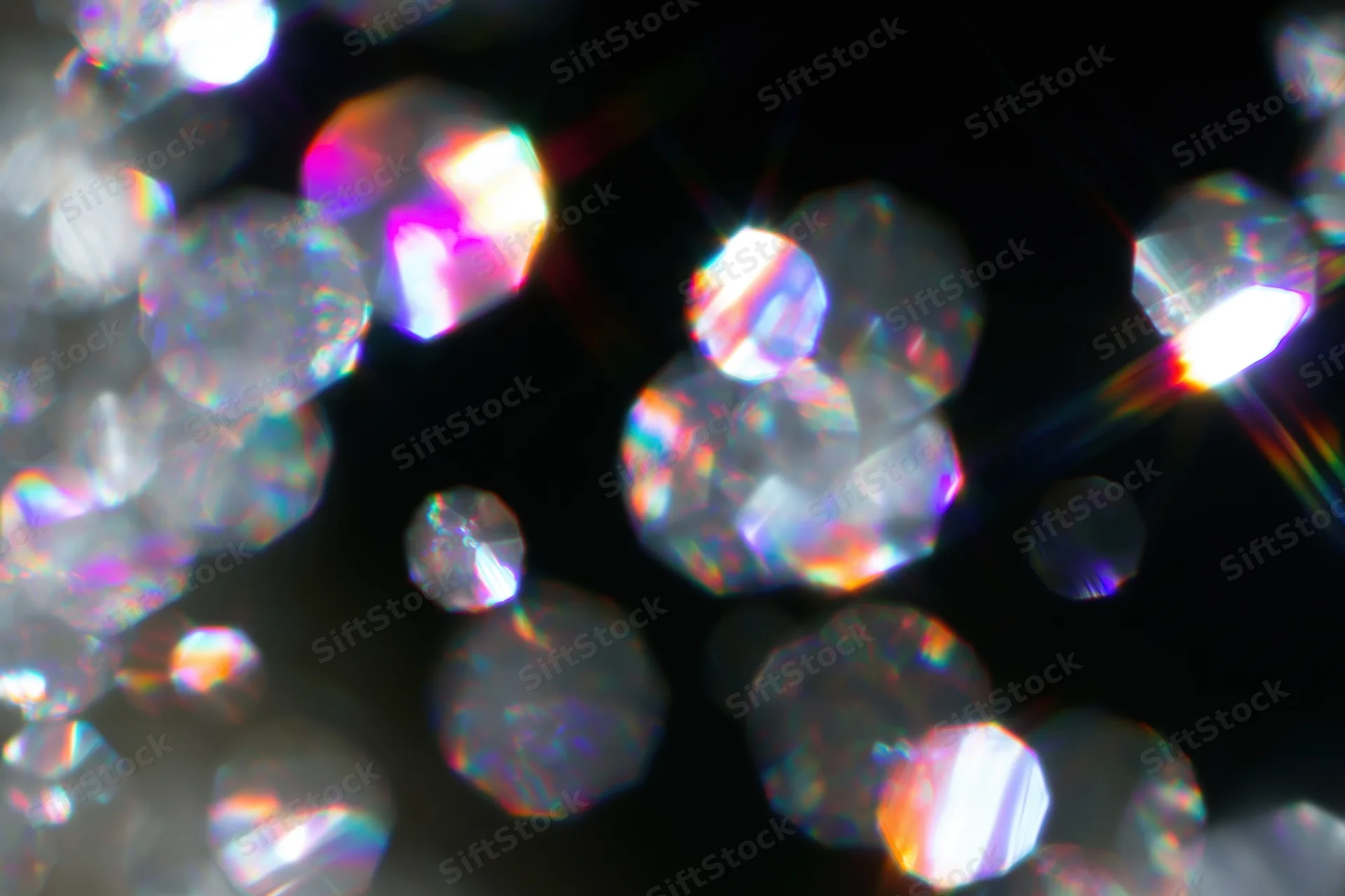 Scattered prismatic light refractions and bokeh circles float against a dark background
