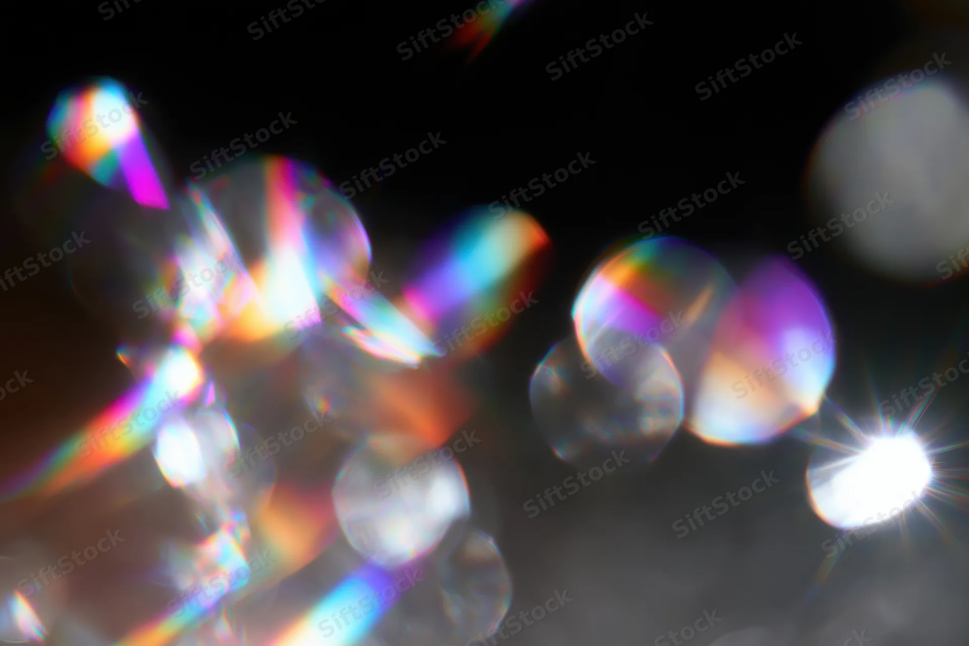 Scattered prismatic light refractions and bokeh circles float against a dark background