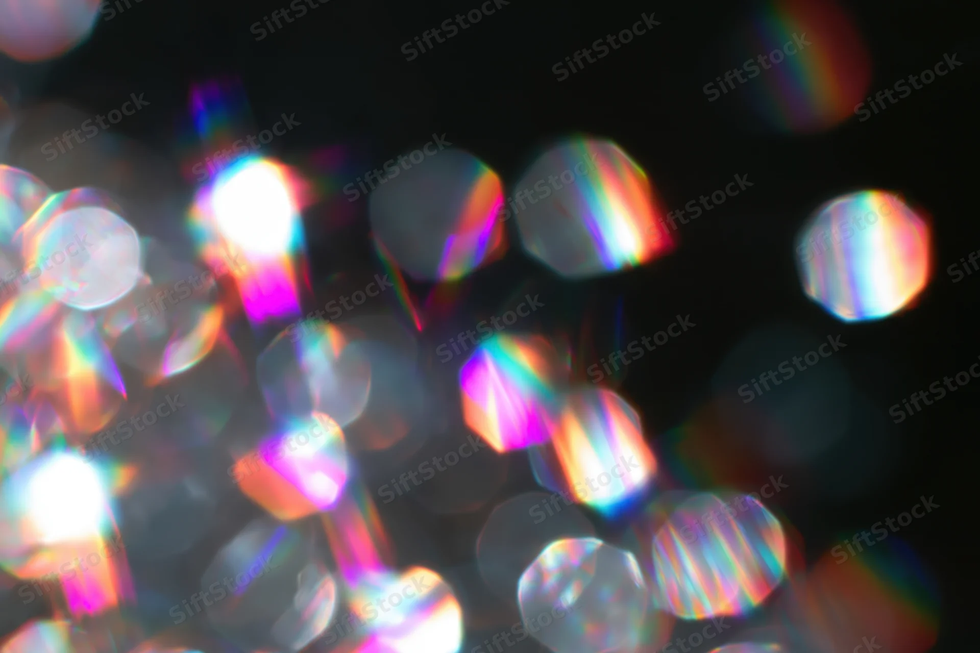 Scattered prismatic light refractions and bokeh circles float against a dark background