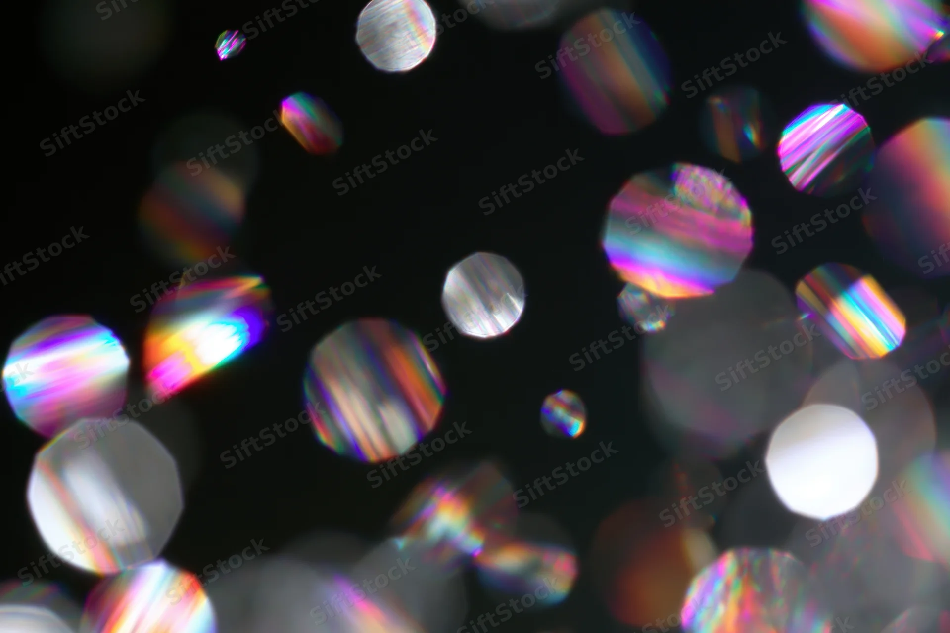 Scattered prismatic light refractions and bokeh circles floating against a dark background