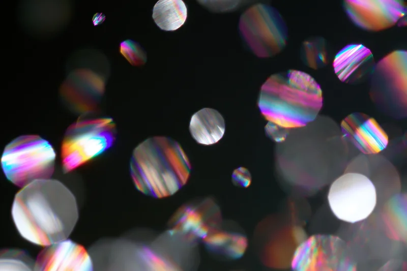Scattered prismatic light refractions and bokeh circles floating against a dark background
