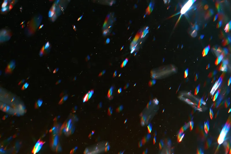 Scattered prismatic light refractions floating against a dark background