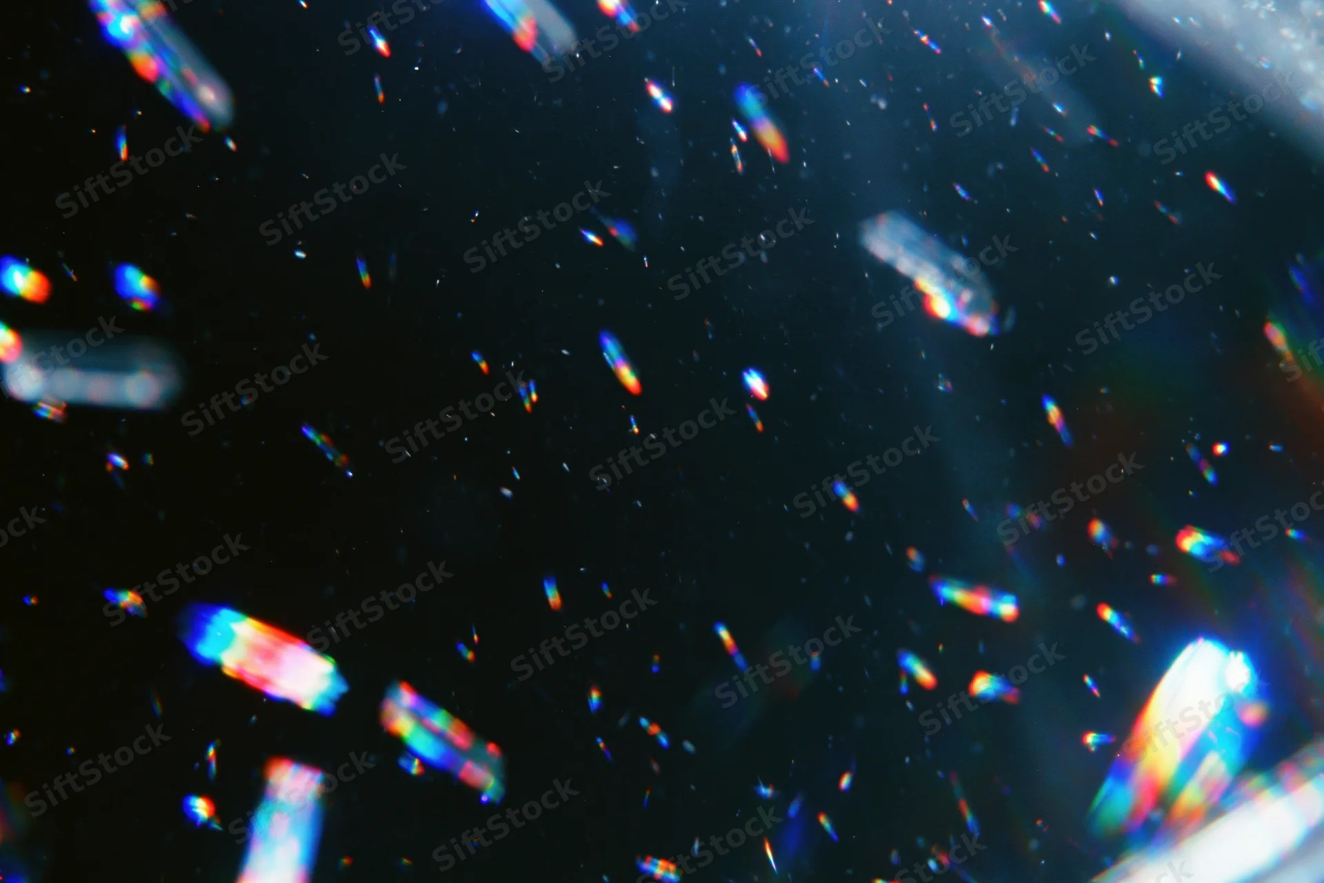 Scattered prismatic light refractions floating against a dark background