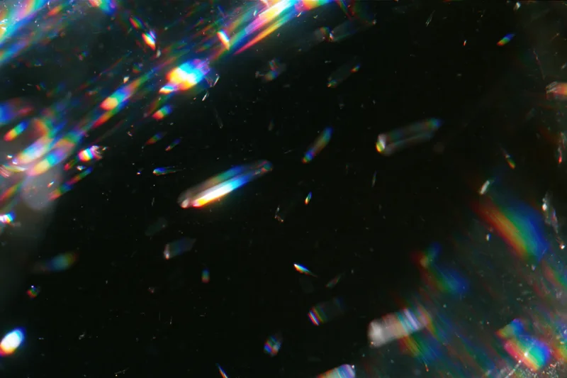 Scattered prismatic light refractions floating against a dark background
