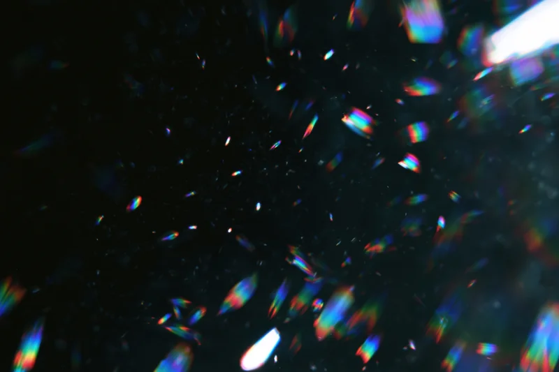 Scattered prismatic light refractions floating against a dark background