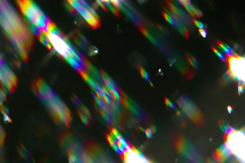 Scattered rainbow light refractions and prismatic lens flares across a dark background