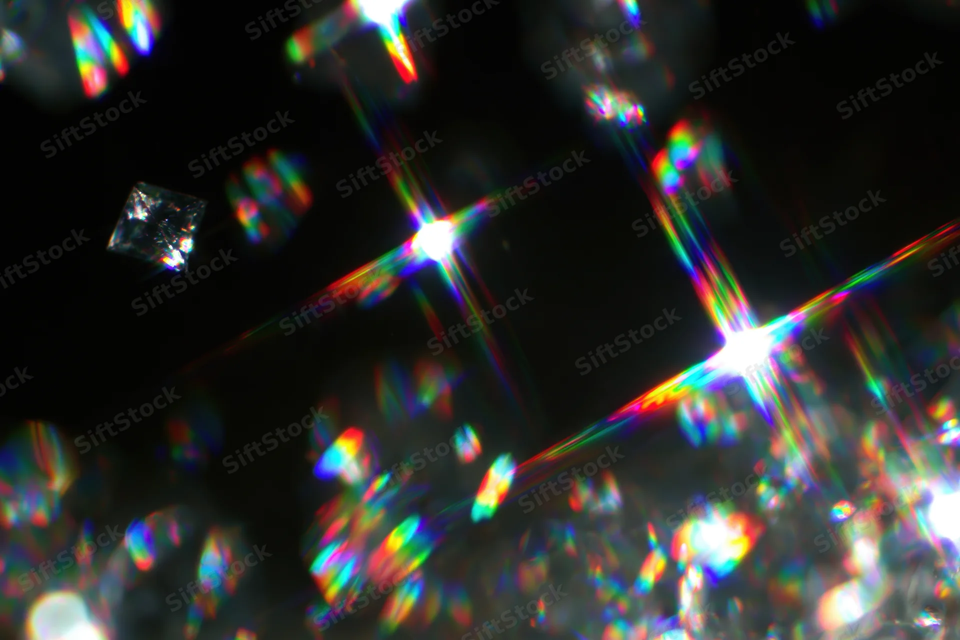 Scattered rainbow light refractions and prismatic lens flares against dark background