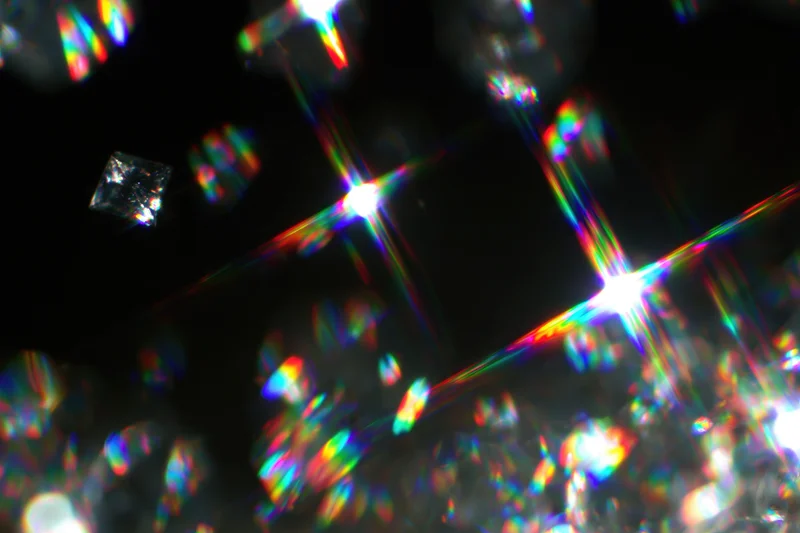 Scattered rainbow light refractions and prismatic lens flares against dark background