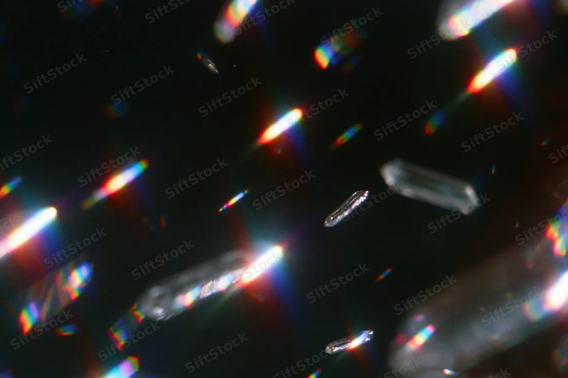 Scattered rainbow light refractions floating against a dark background