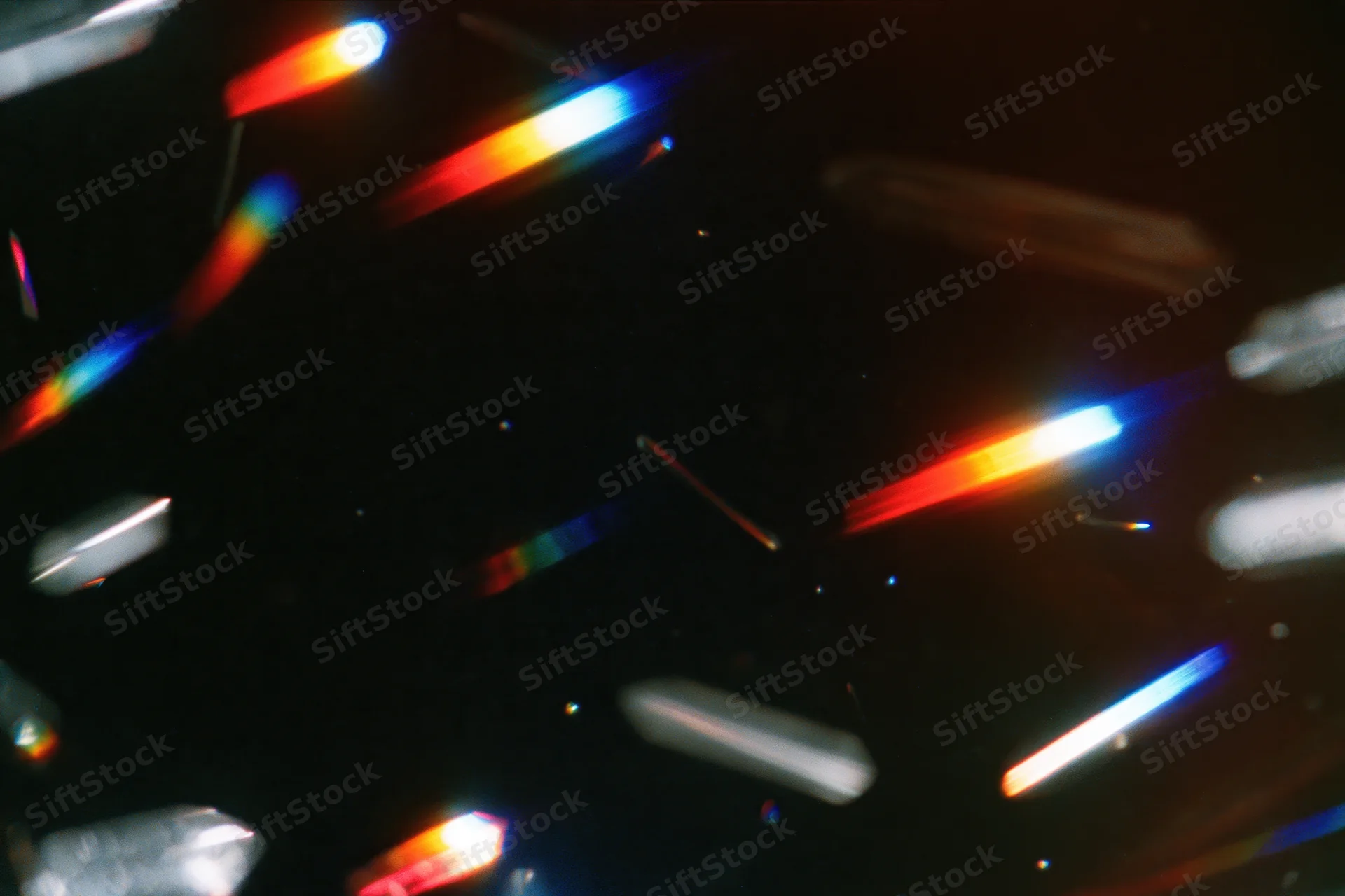 Scattered rainbow light refractions floating against a dark background