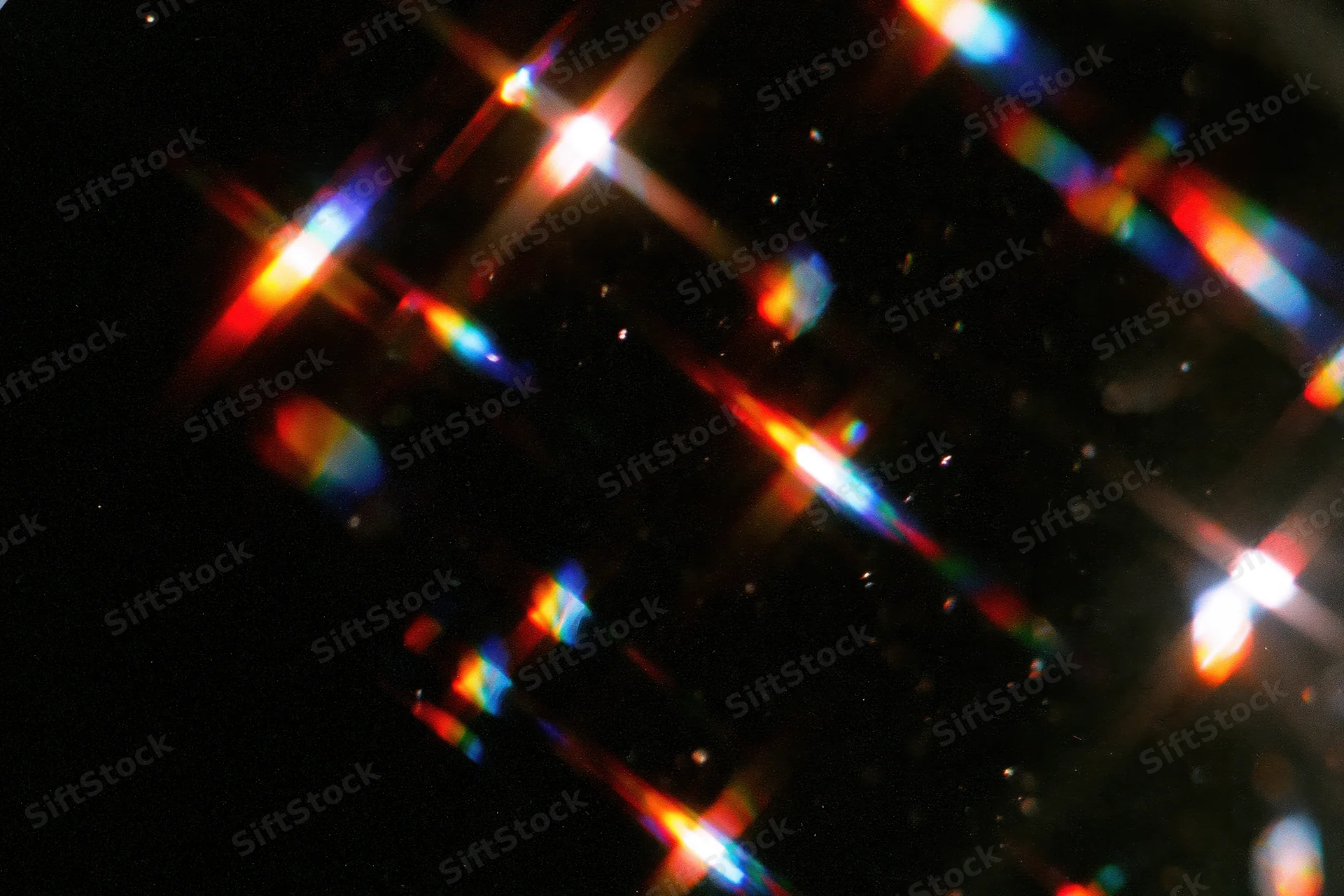 Scattered rainbow light refractions floating against a dark background