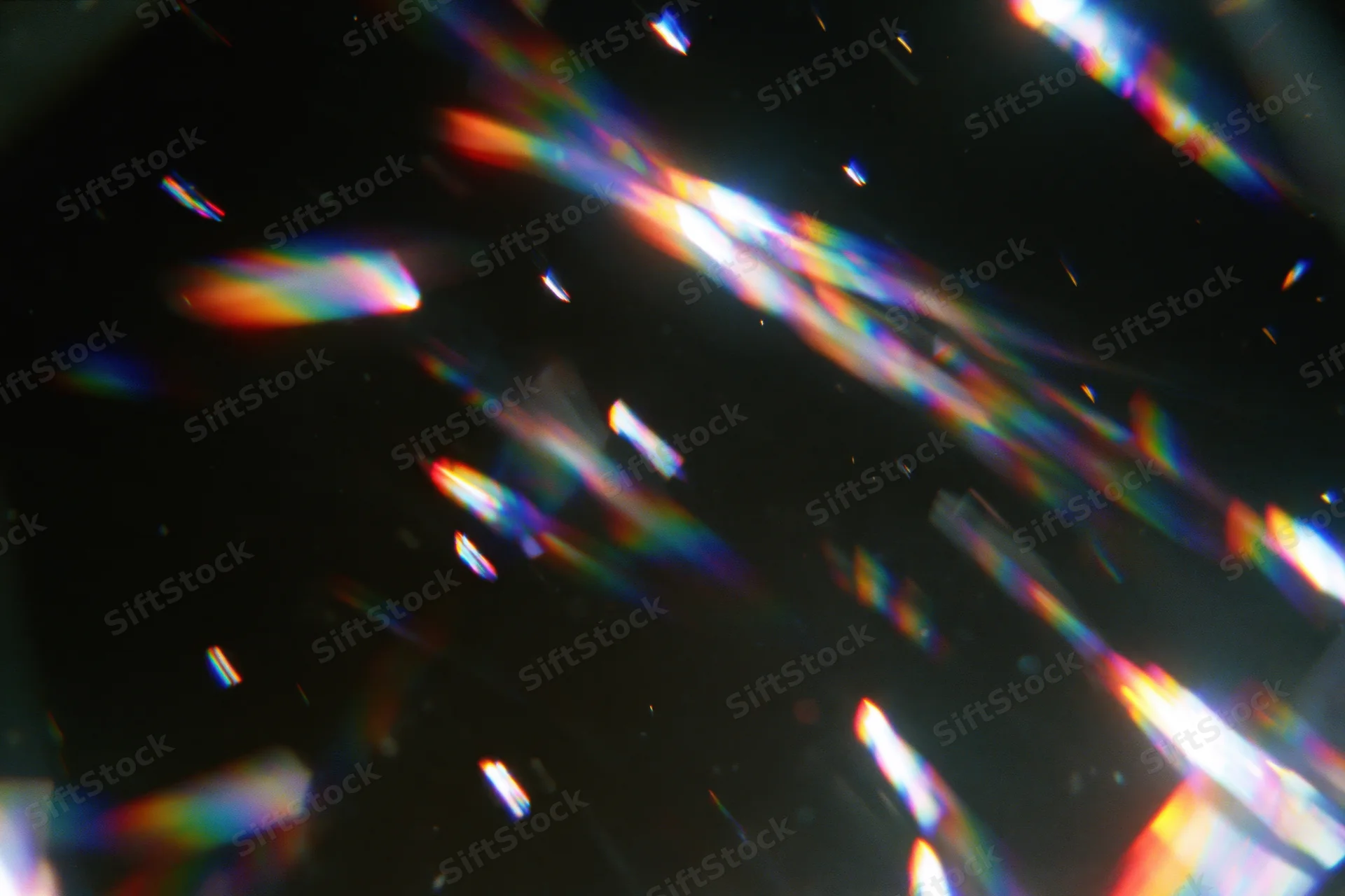 Scattered rainbow light refractions floating against a dark background