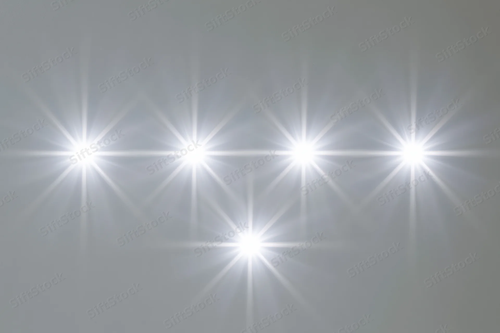 Six bright white lens flare star bursts arranged in two rows against a neutral gray background