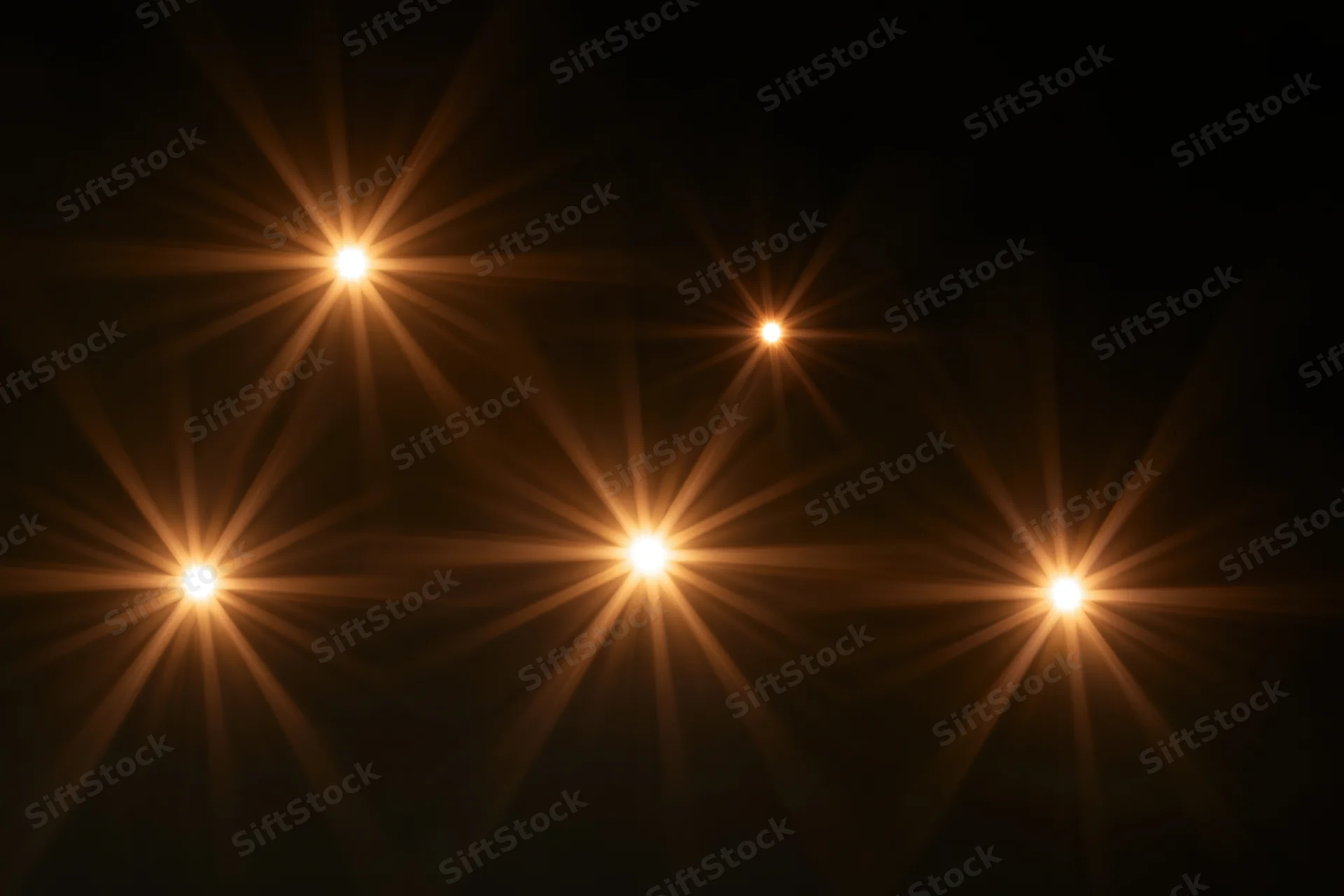 Golden lens flare star bursts scattered across a dark background