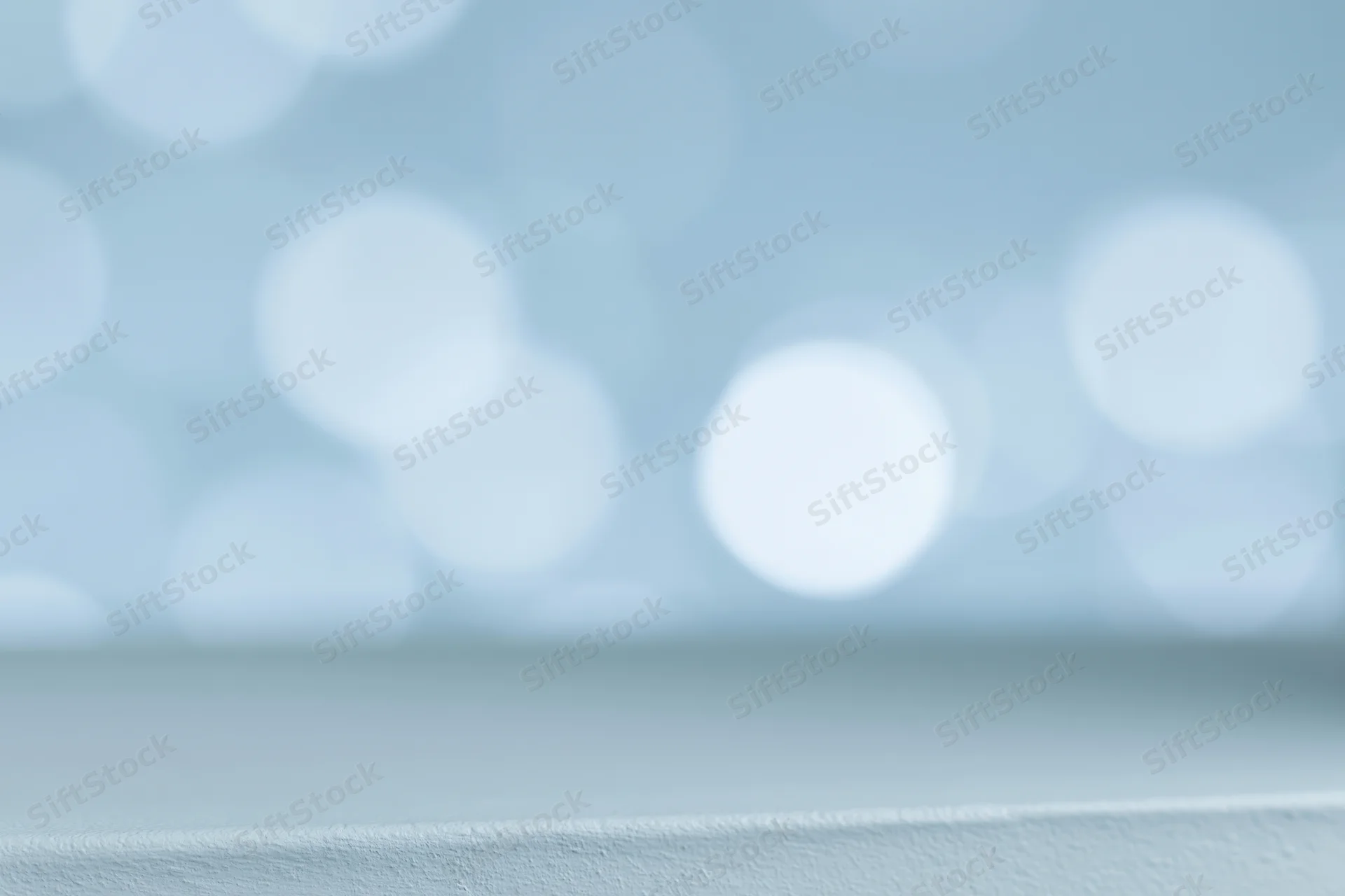 Soft defocused bokeh circles in light blue and white on a smooth surface with copyspace