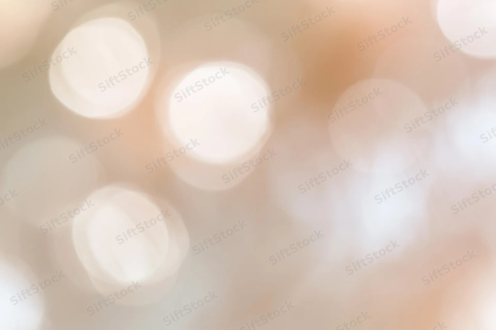 Soft abstract bokeh background with large out-of-focus lights in warm tones