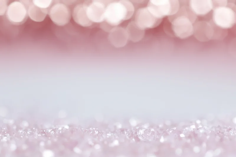 Soft pink bokeh background with out-of-focus light orbs and glittery texture, featuring copyspace in the center