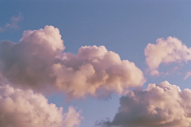 Soft cumulus clouds drifting across an open daytime sky