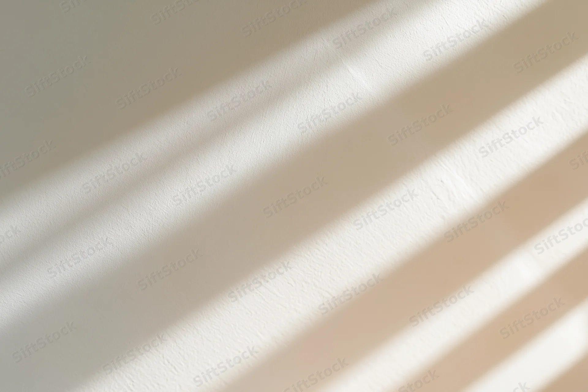 Diagonal window light shadows cast across a plain warm wall in an interior space