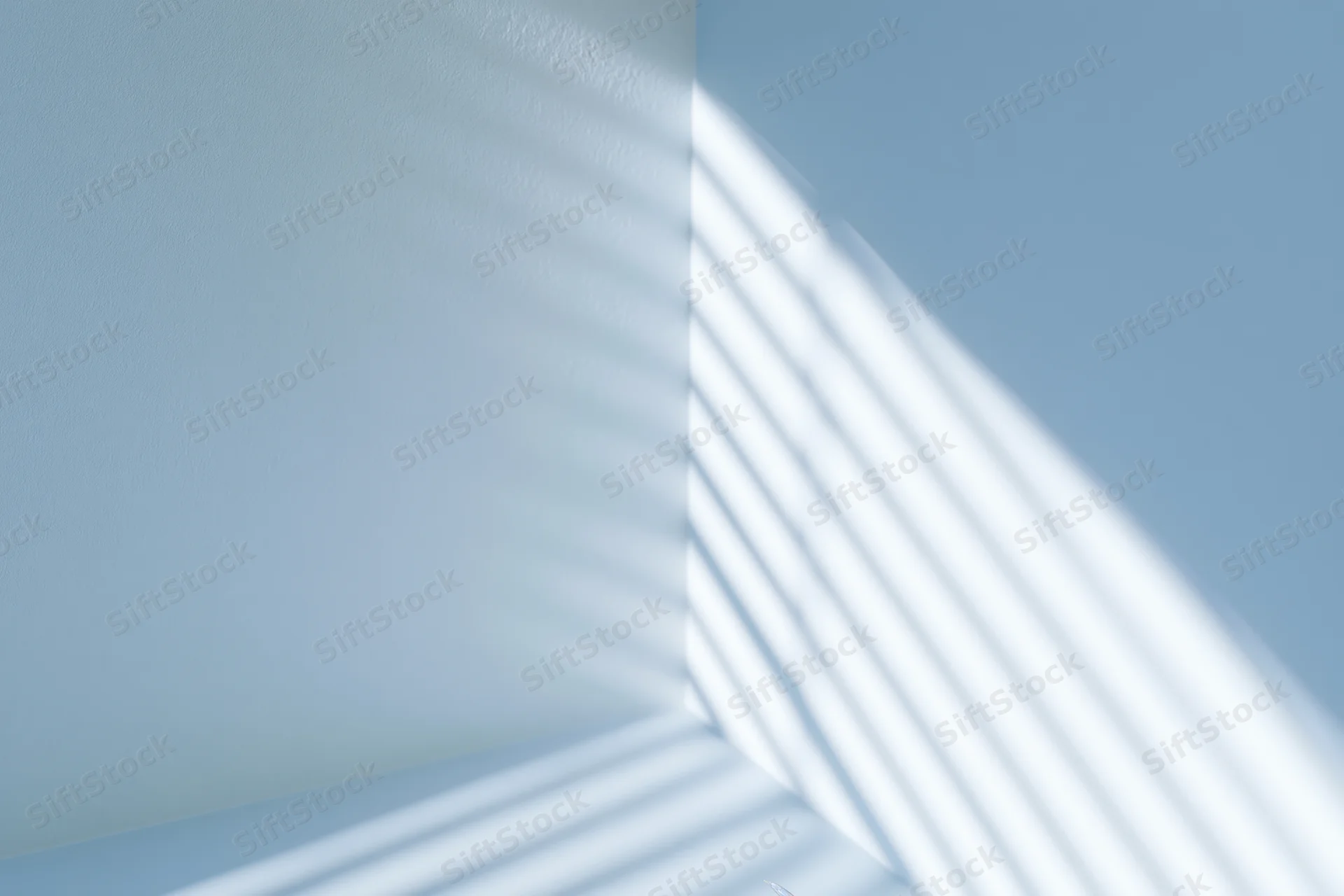 Diagonal light and shadow stripes cast across a blue interior wall corner