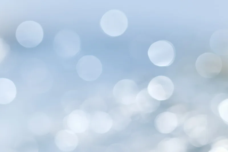 Soft out-of-focus circular lights scattered across a pale blue gradient background