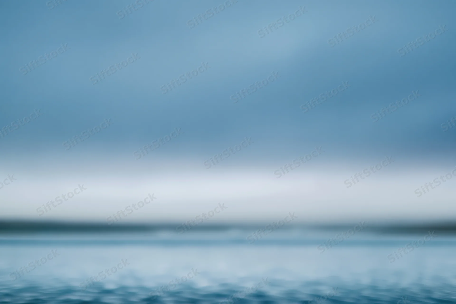 Soft blurred gradient of blue sky and water with indistinct horizon line