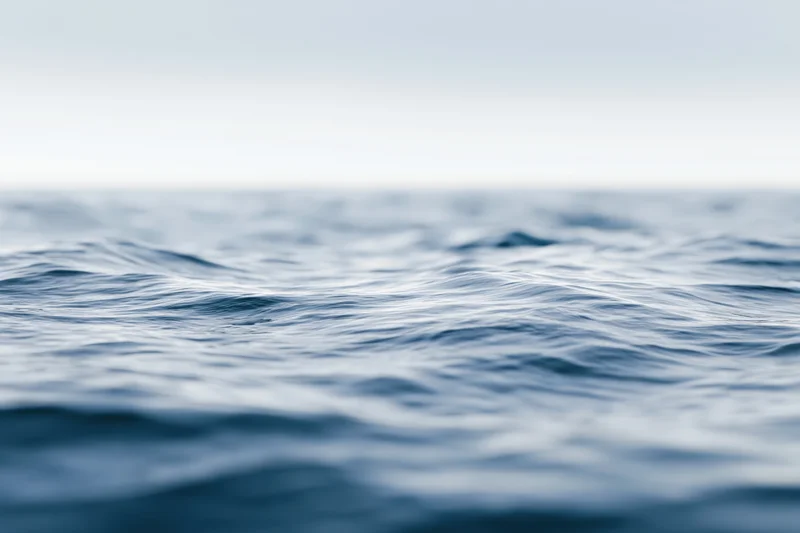 Soft blurred ocean surface with gentle waves at water level under overcast sky