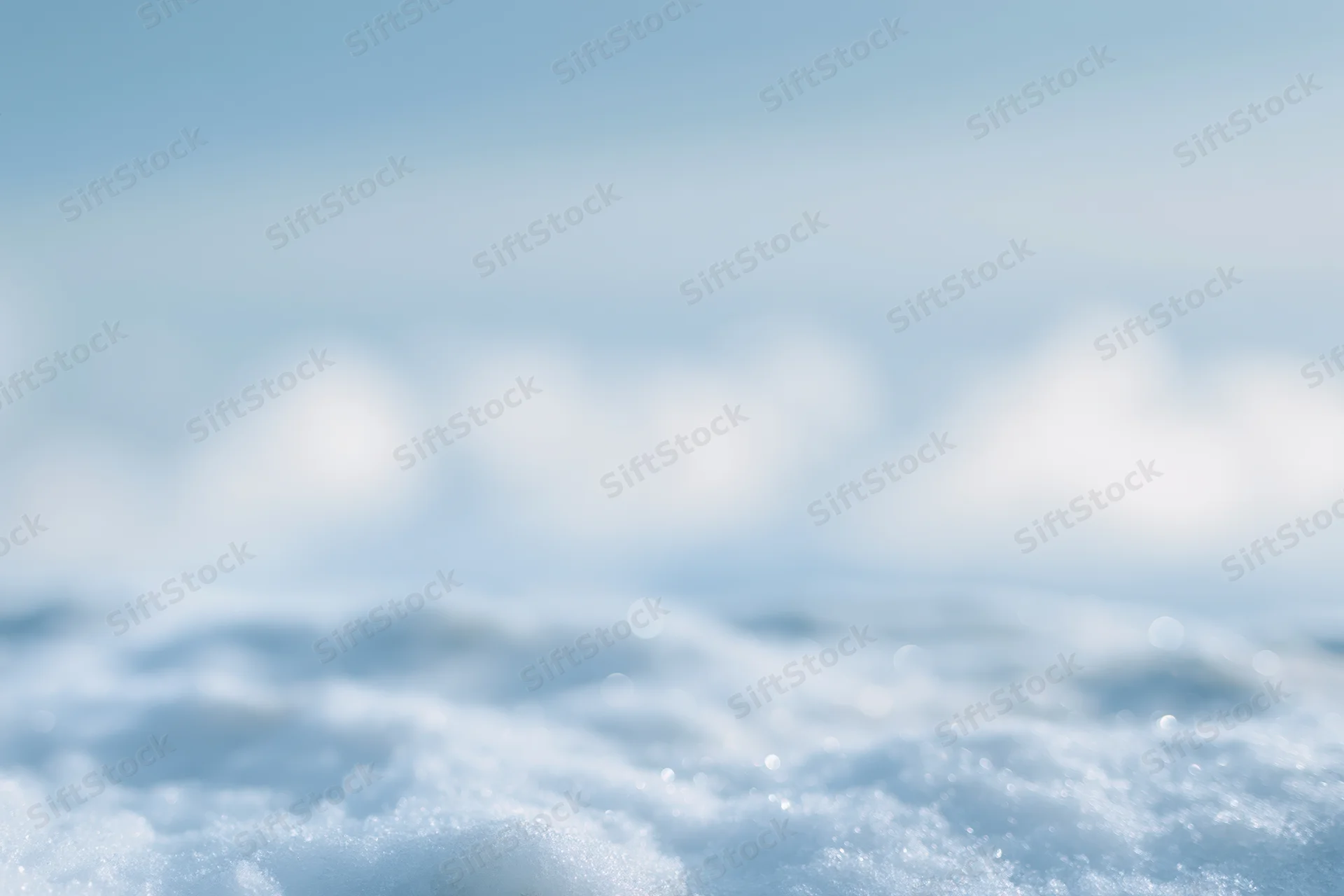 Soft out-of-focus snow surface under winter daylight sky with bokeh effect