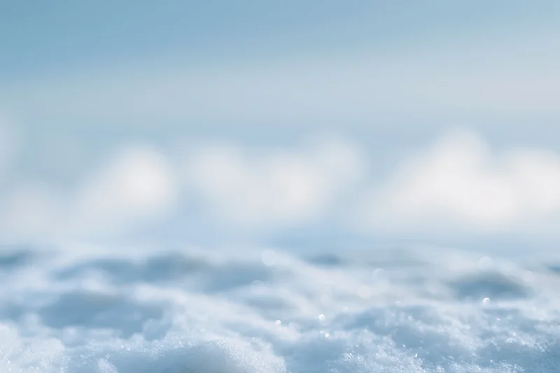Soft out-of-focus snow surface under winter daylight sky with bokeh effect
